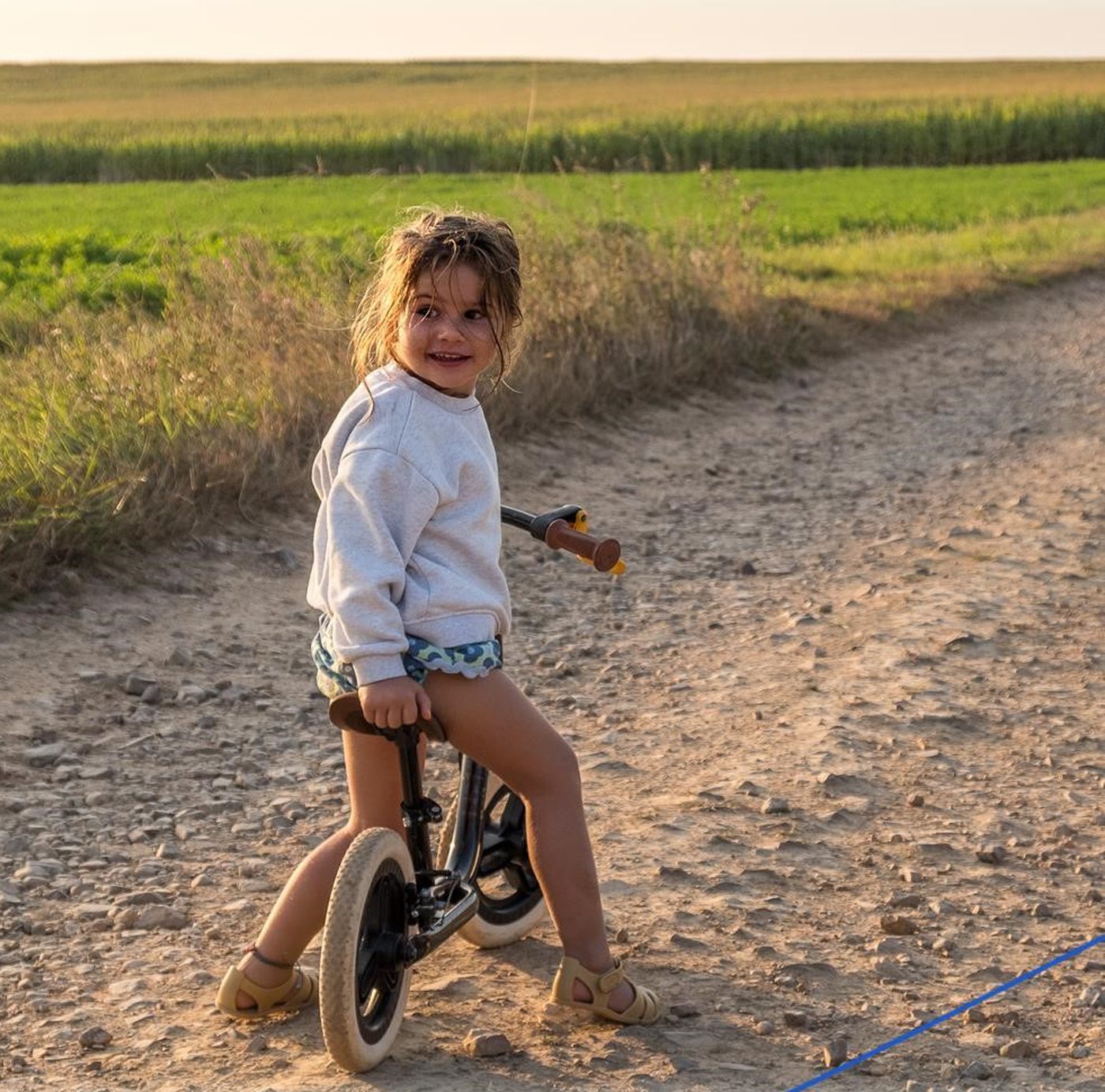 Carlota, de 4 años, sobre su bicicleta en un camino de tierra al atardecer